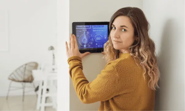 Young woman using her wall mounted security system tablet