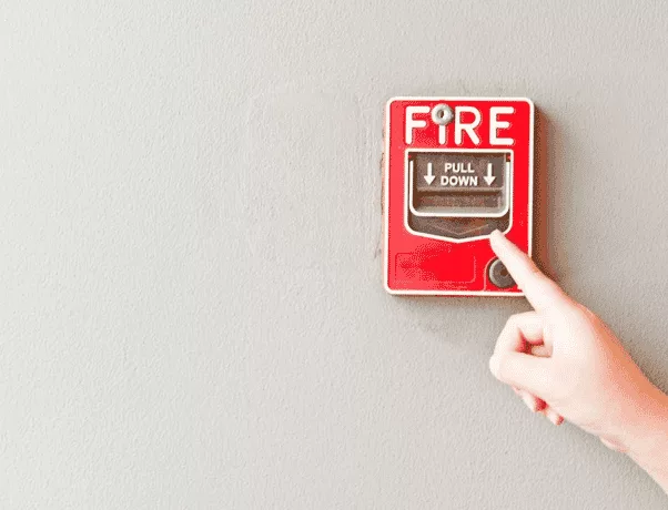 A finger pointing to a pulldown fire alarm
